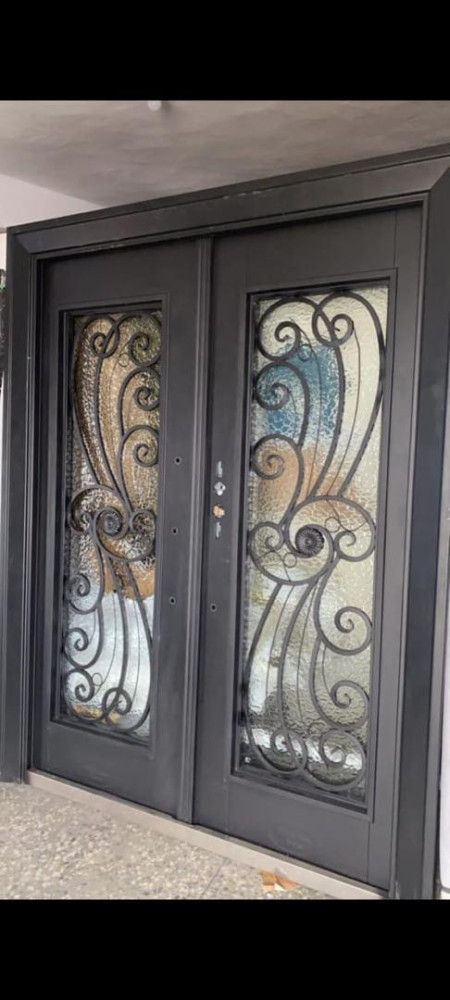 Wrought iron double doors featuring a decorative scroll design with frosted glass or textured glass