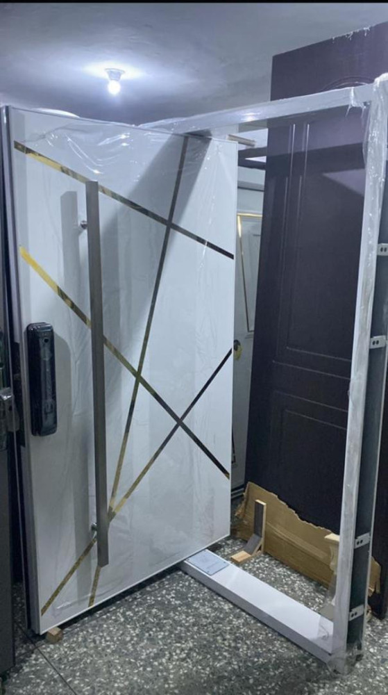 Modern White Pivot Scurity Door with gold-tone metal accents and a smart lock